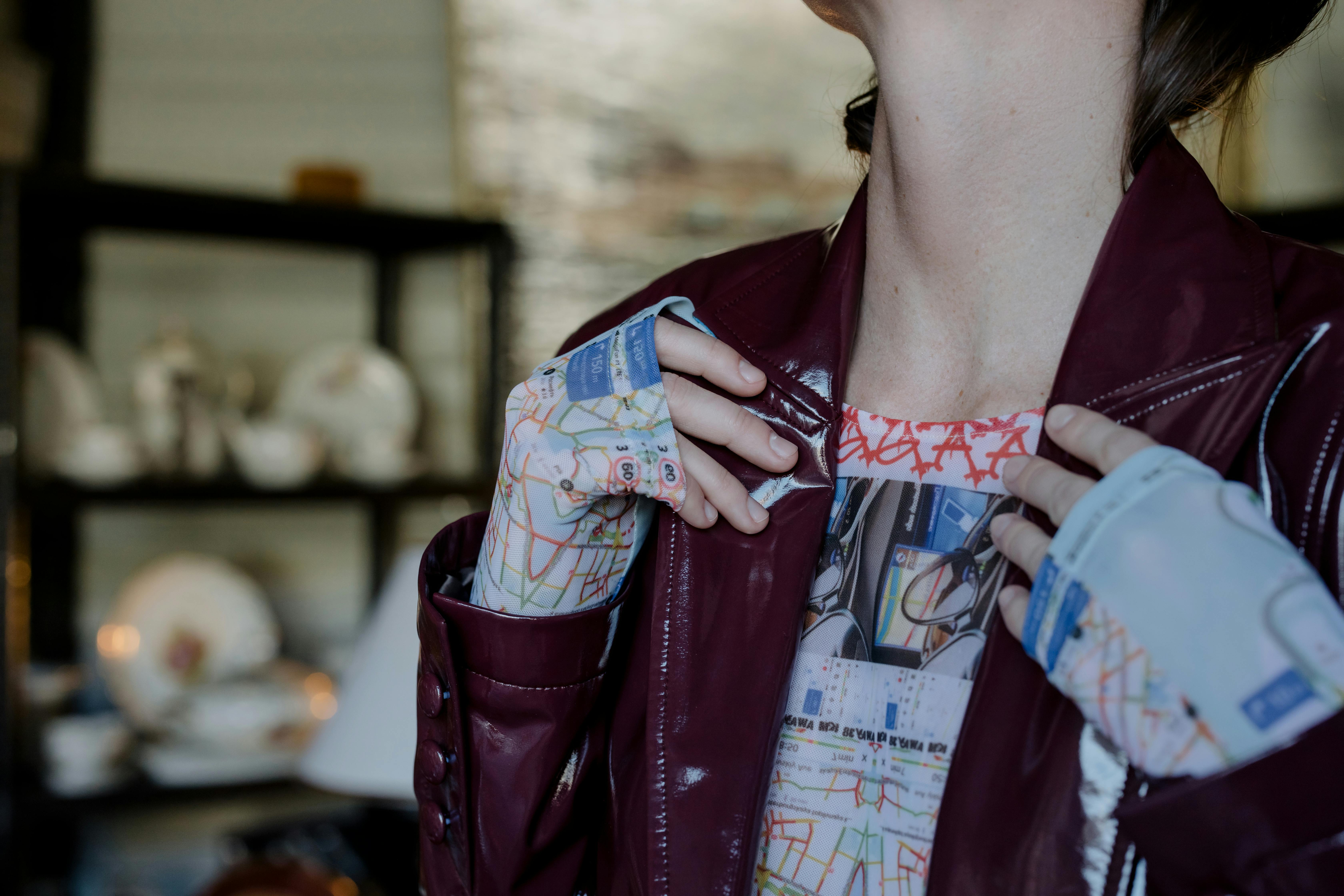 Close-up fashion shot highlighting a printed shirt and maroon leather jacket.