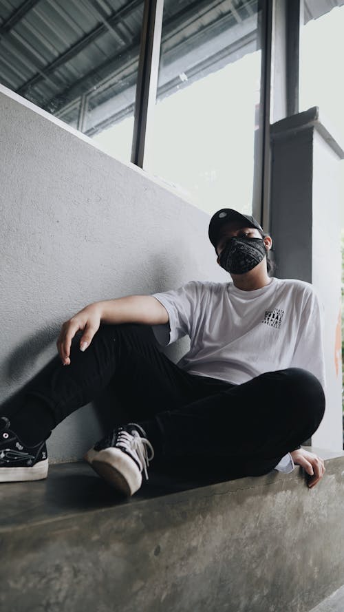 A Person in White Shirt and Black Pants Sitting on the Corner