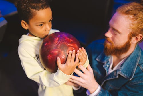 Boy Holding a Bowling Ball Beside a Man