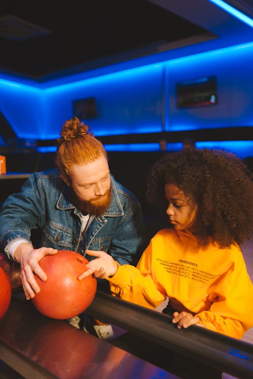 Close-Up Shot of Father and Daughter Holding Bowling Ball