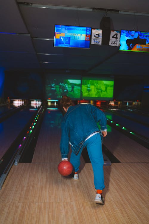 A Person in Blue Denim Jacket Playing Bowling