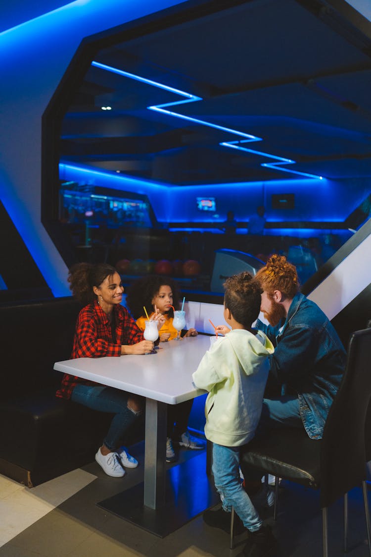 Parents With Kids Sitting At The Table Drinking Juice