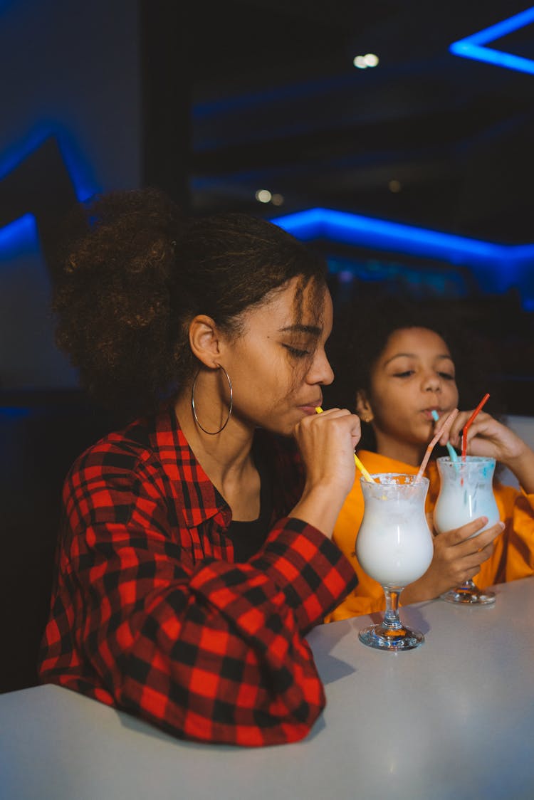 Two Girls Drinking Beverages Together