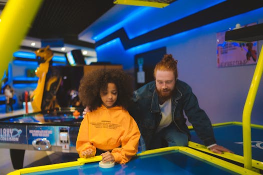 A man and girl enjoying a game of air hockey in a vibrant arcade setting.