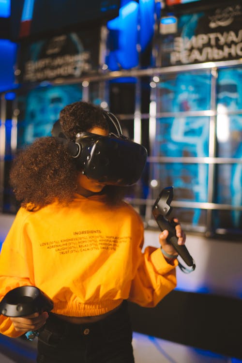 A Girl in Yellow Jacket Wearing a Vr Goggles and Holding a Game Controller