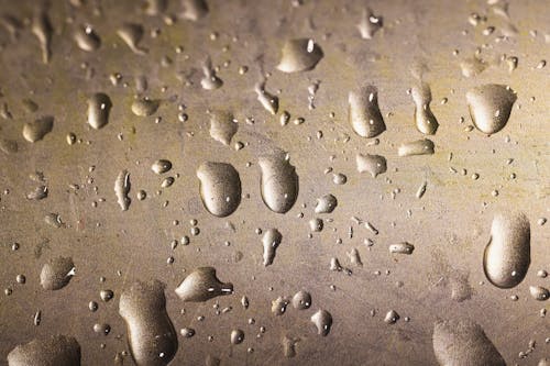 Close-Up Shot of Water Droplets on a Gold Surface