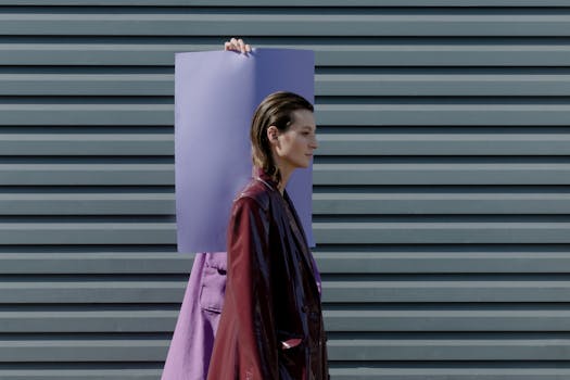 Modern fashion model posing outdoors with purple panel against striped wall.