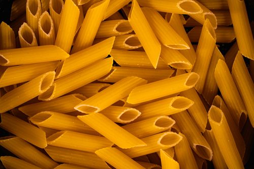 Free High-definition close-up of uncooked penne pasta, showcasing texture and detail. Stock Photo