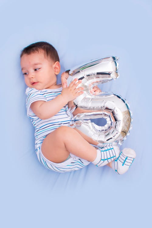 A Toddler Holding a Number Balloon