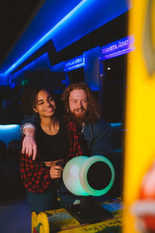 Free A happy couple enjoys a fun time playing a video game at a vibrant arcade setting. Stock Photo