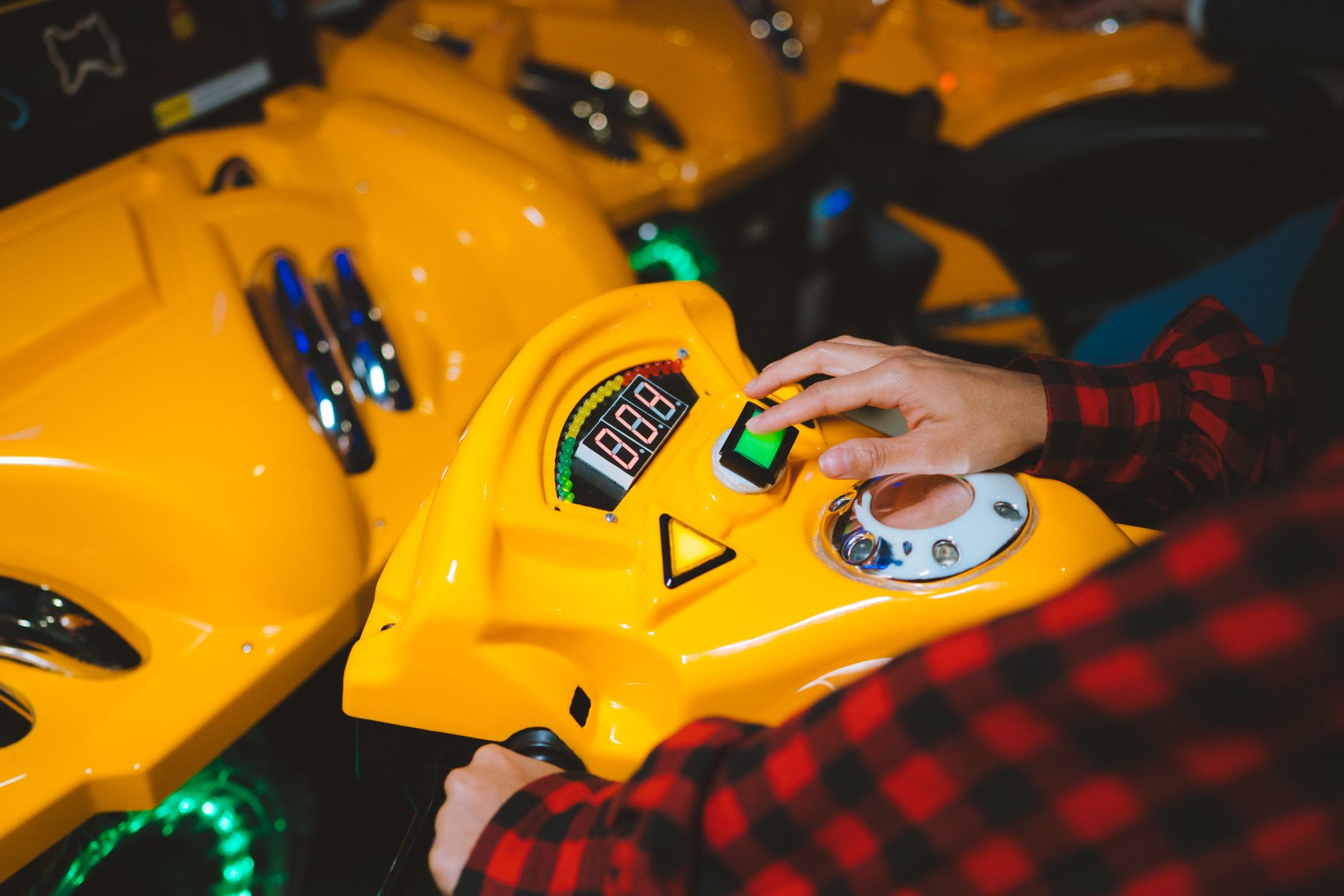 arcade games rental cairo — Close-up of a person playing an arcade game with a yellow console and colorful lights.