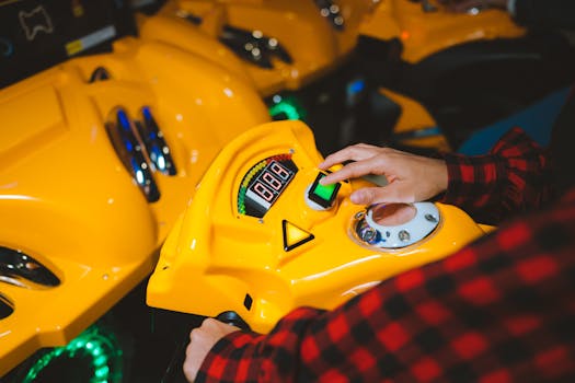 Close-up of a person playing an arcade game with a yellow console and colorful lights.