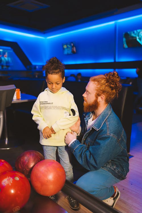 A Man Teaching a Kid to Play Bowling