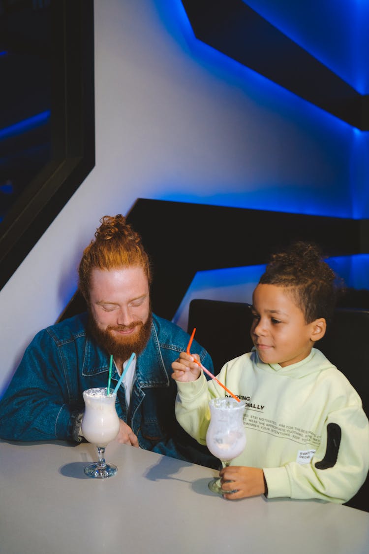 A Man And A Kid Drinking Juice At The Table