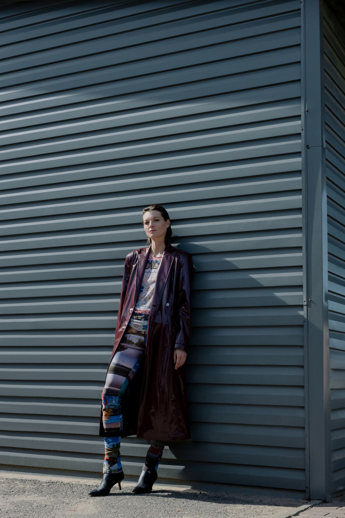 Fashion model in a maroon leather coat captured in a tall vertical urban composition
