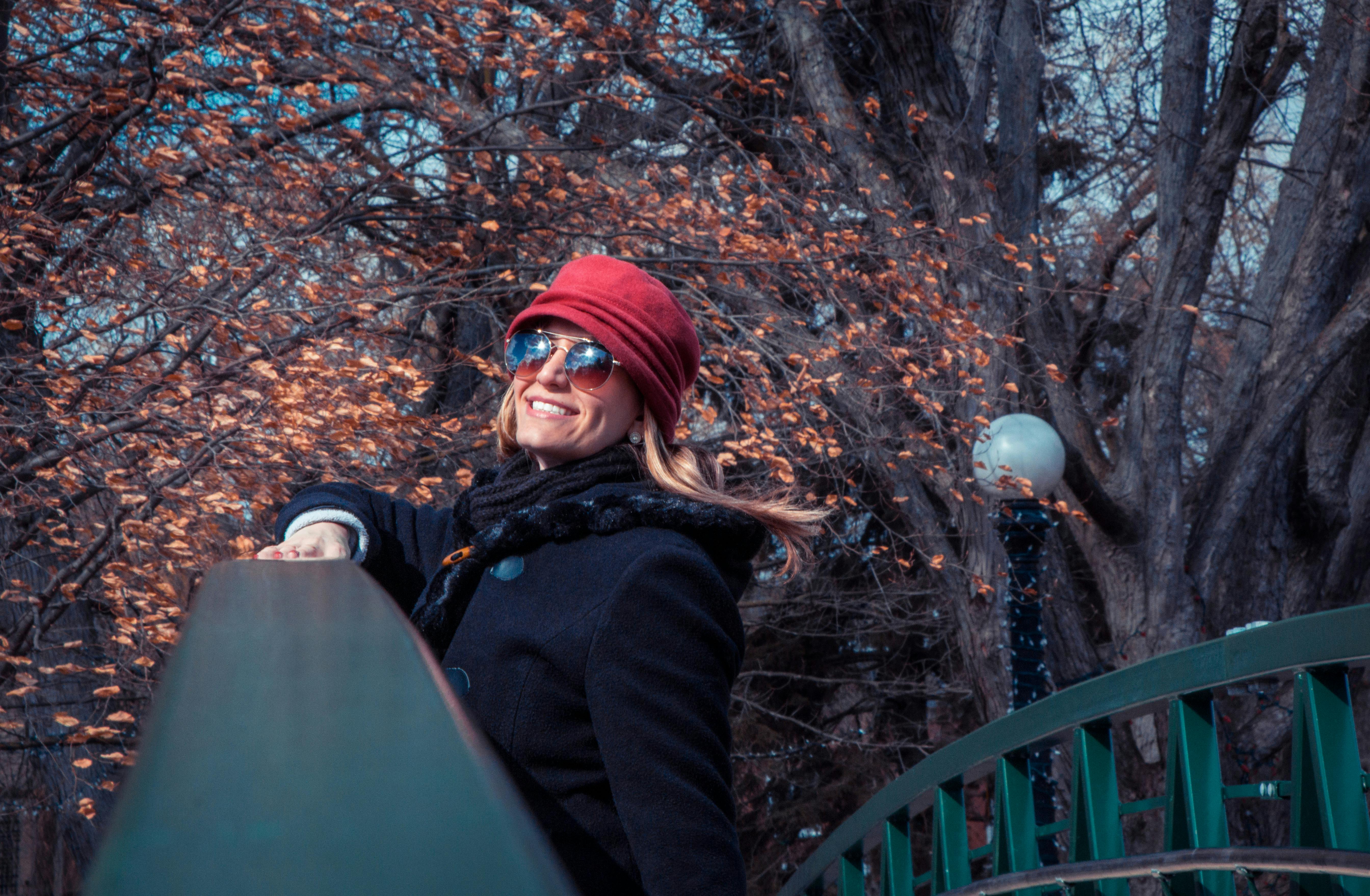 在加拿大基奇纳的秋日里，一位戴着红帽子和太阳镜的女子在户外微笑