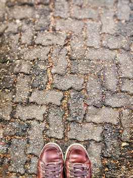 Brown leather shoes standing on rustic cobblestone street. Ideal for travel and lifestyle themes.