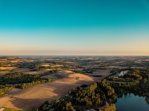 Free Breathtaking aerial landscape of Erechim, Brazil, showcasing rolling hills, fields, and a serene lake at sunset. Stock Photo