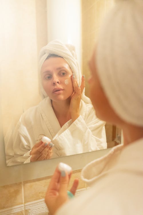 Free A Woman Applying Facial Cream on Her Face Stock Photo