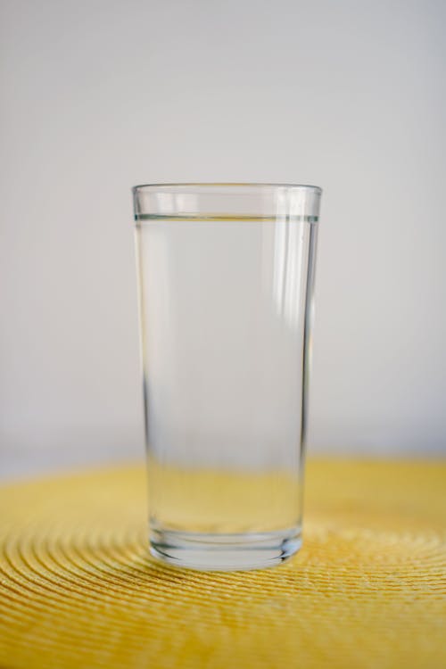 Free Clear Drinking Glass on Yellow Textile Stock Photo