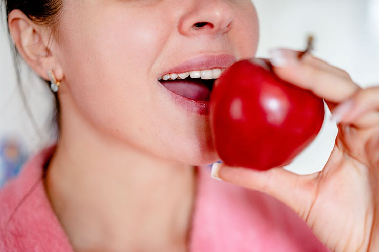 Close-Up Shot Of A Woman Biting An Apple