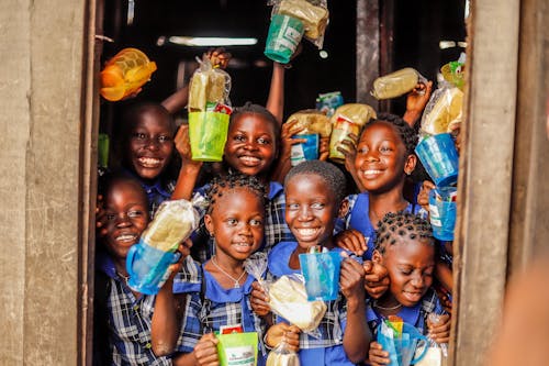 A group of African children smiling and holding food 