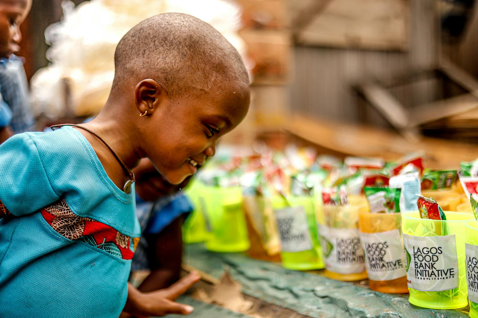 A smiling child engages with the Lagos Food Bank Initiative, showcasing joy and community support.