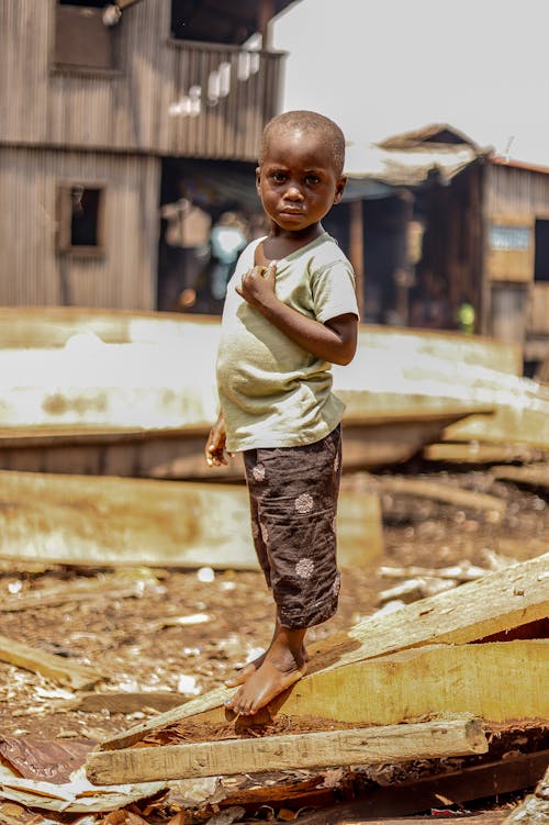 A Barefooted Boy Standing on Wooden Board
