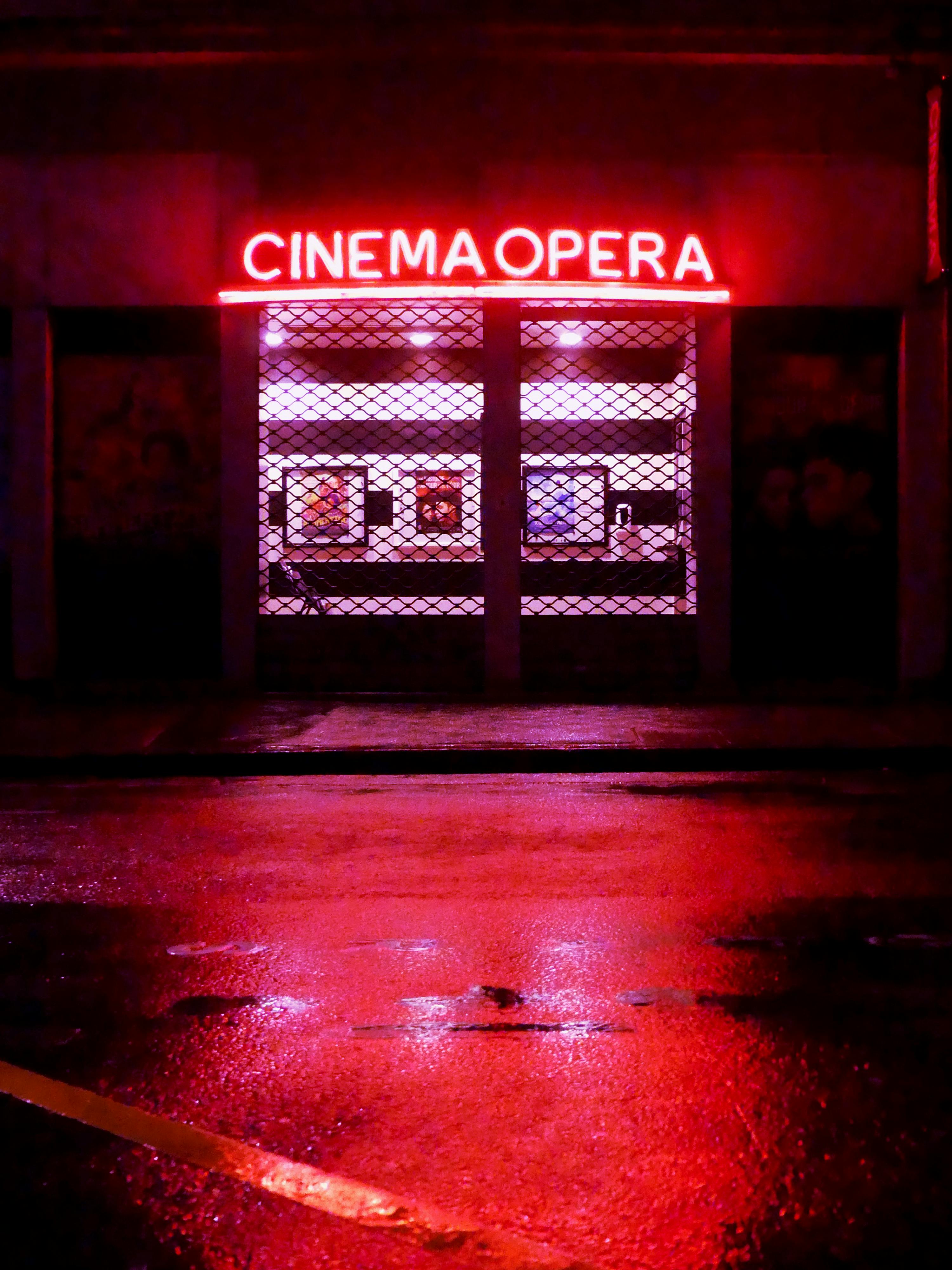 Free Vibrant red neon sign of Cinema Opera reflecting on wet streets of Lyon at night. Stock Photo
