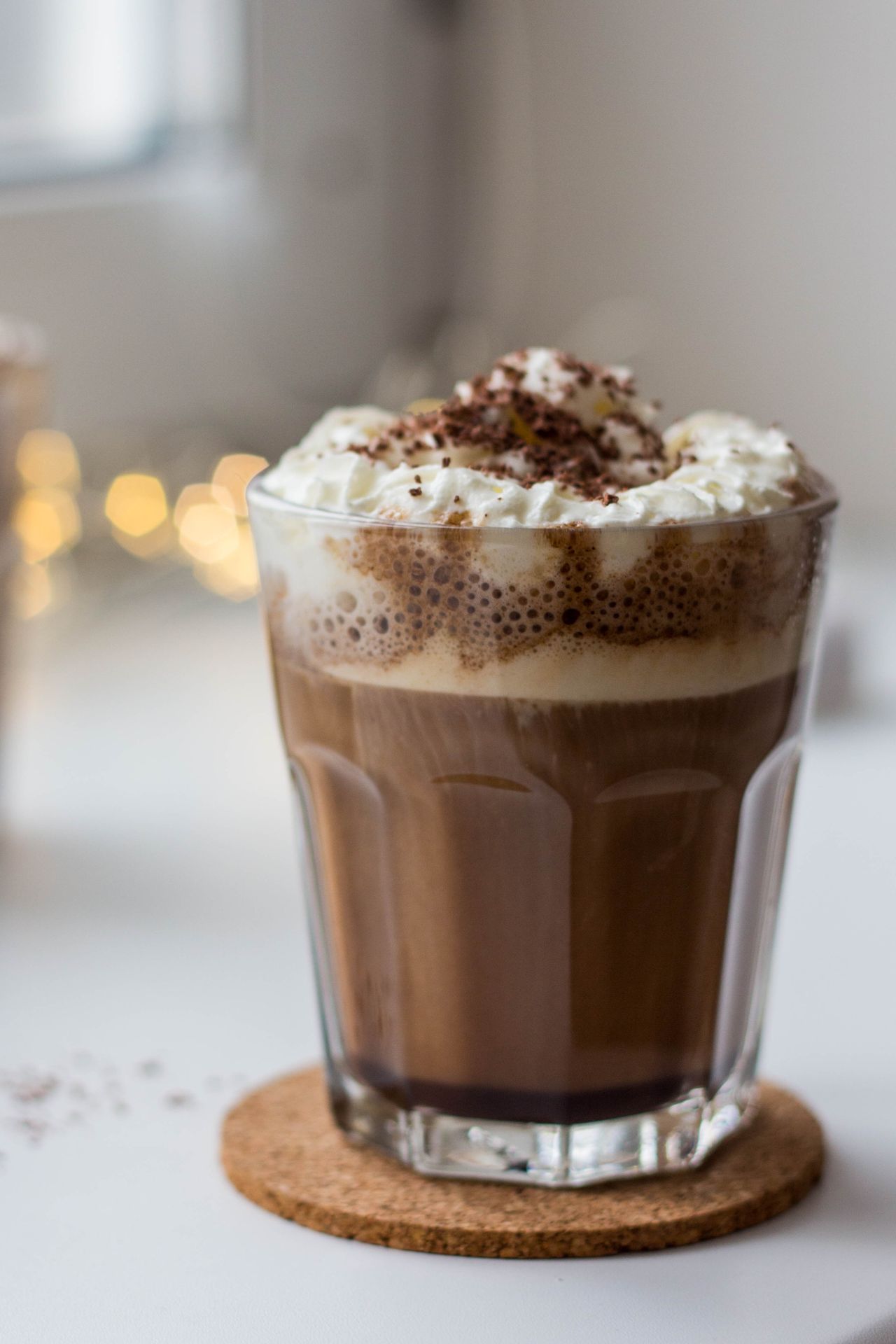 Hot chocolate with whipped cream and chocolate shavings in a cozy room