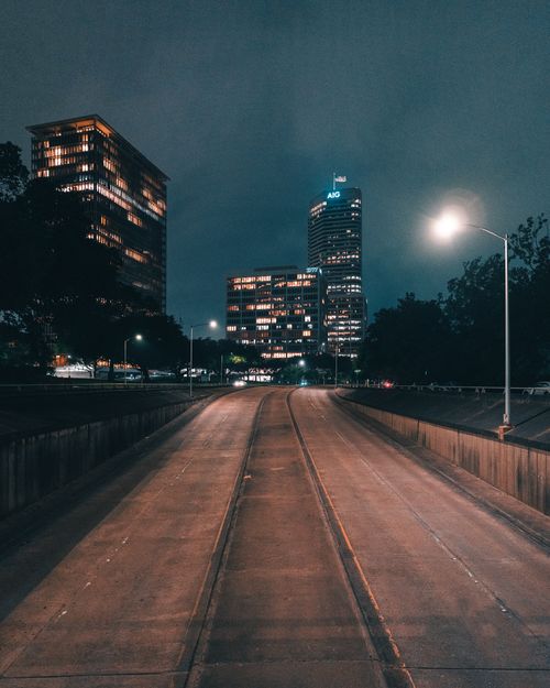 Free Night view of an empty road leading to Houston's skyline with illuminated buildings and street lights. Stock Photo