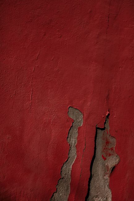 Detailed view of a textured and cracked red wall, perfect for backgrounds or design elements.
