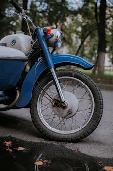 Detailed view of vintage motorcycle's front wheel and suspension on a street.
