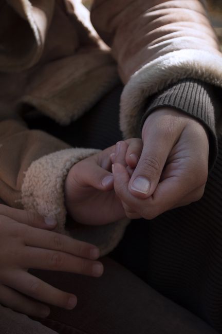 Fotomural Una imagen reconfortante que muestra a un adulto y un niño tomados de la mano en un gesto de calidez y afecto.