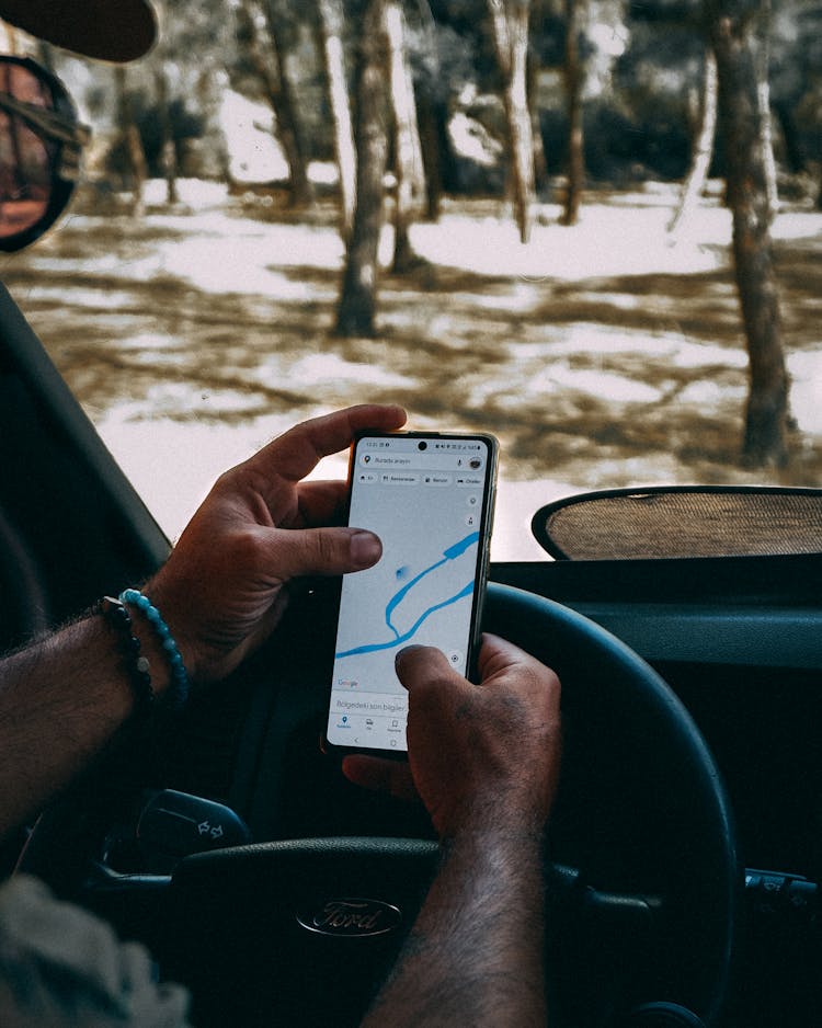 Man Looking At Directions On His Smart Phone In A Car