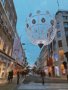 A bustling urban street adorned with holiday lights and high-end retail stores, creating a festive city atmosphere.