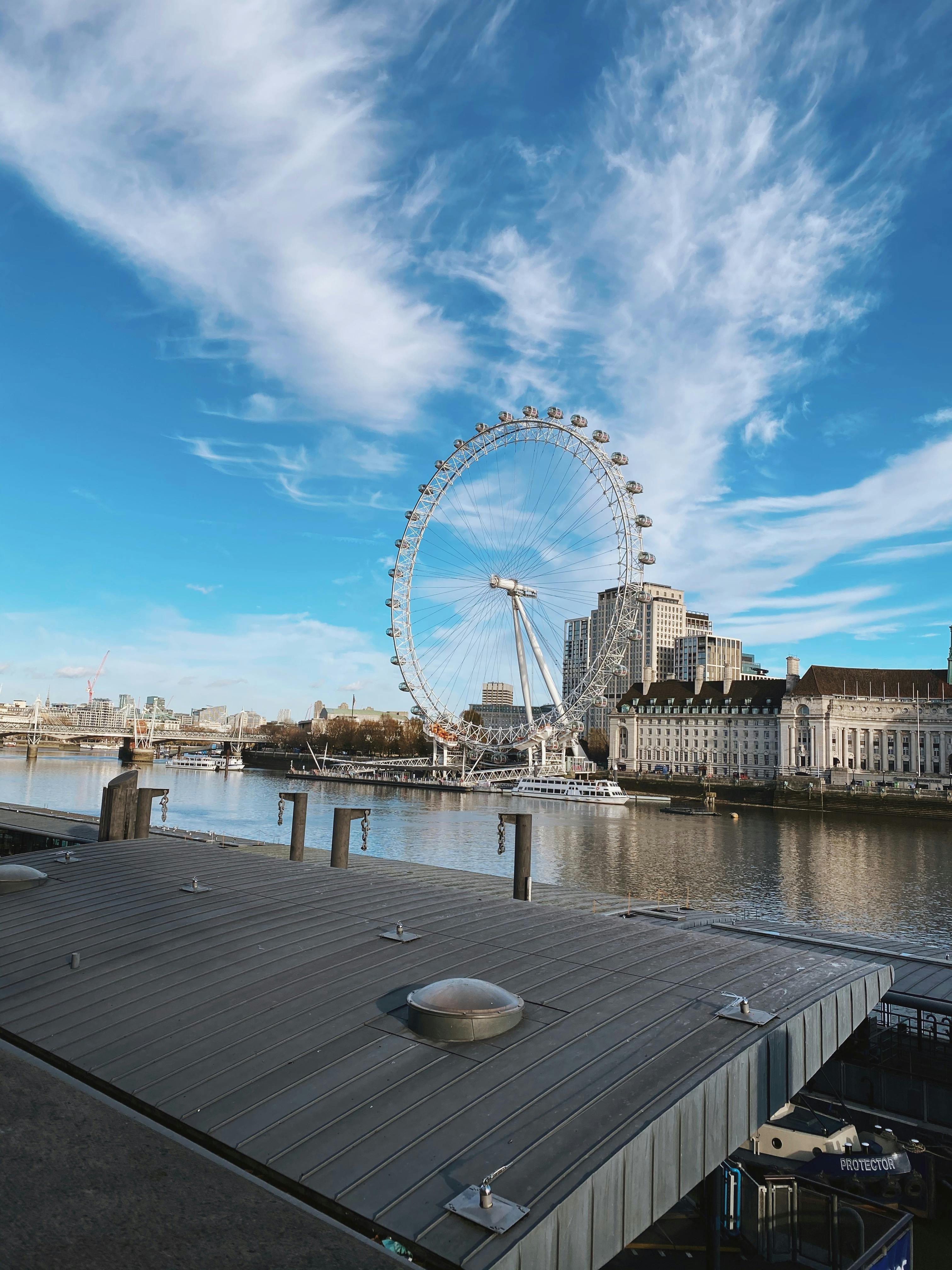 Beautiful capture of the London Eye against a clear blue sky over the River Thames.