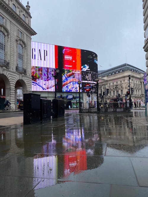 Billboards Reflecting on a Wet Sidewalk in a City 