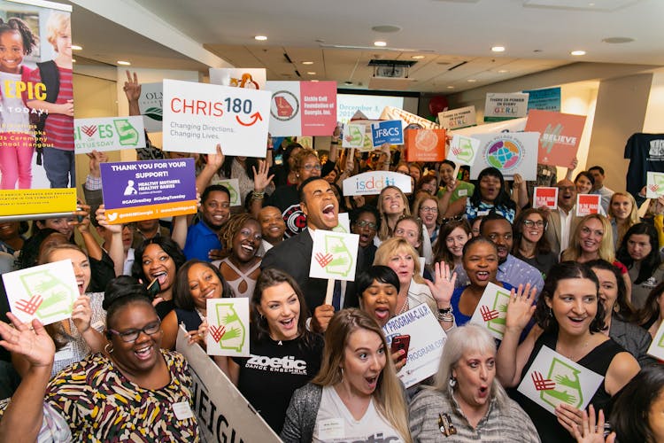 A Large Group Of People Cheering At Charity Event