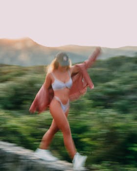 Dynamic image of a woman in a bikini walking with motion blur effect in outdoor natural setting.