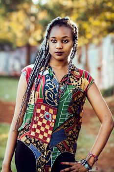 Stylish portrait of a woman outdoors showcasing vibrant fashion and braided hairstyle.