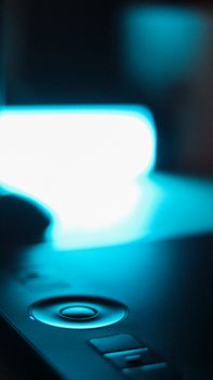 Focused close-up of a tech gadget illuminated by neon light, highlighting modern design.