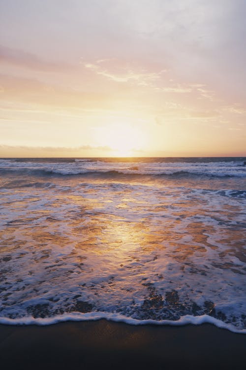 Фотография океанских волн у берега моря во время заката