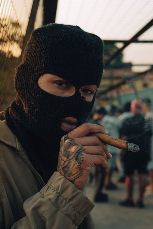 Free Close-up of a person wearing a balaclava and smoking a cigar outdoors, adding mystery and intrigue. Stock Photo