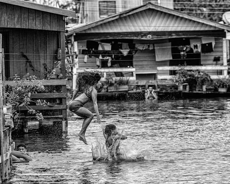 People Jumping Into River From Wooden Houses Terraces