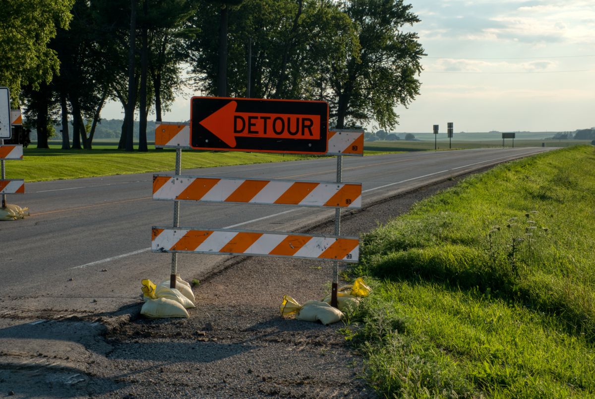 Roadside detour sign with arrow in rural Plainview, MN, under clear skies. Perfect for travel and road maintenance themes.