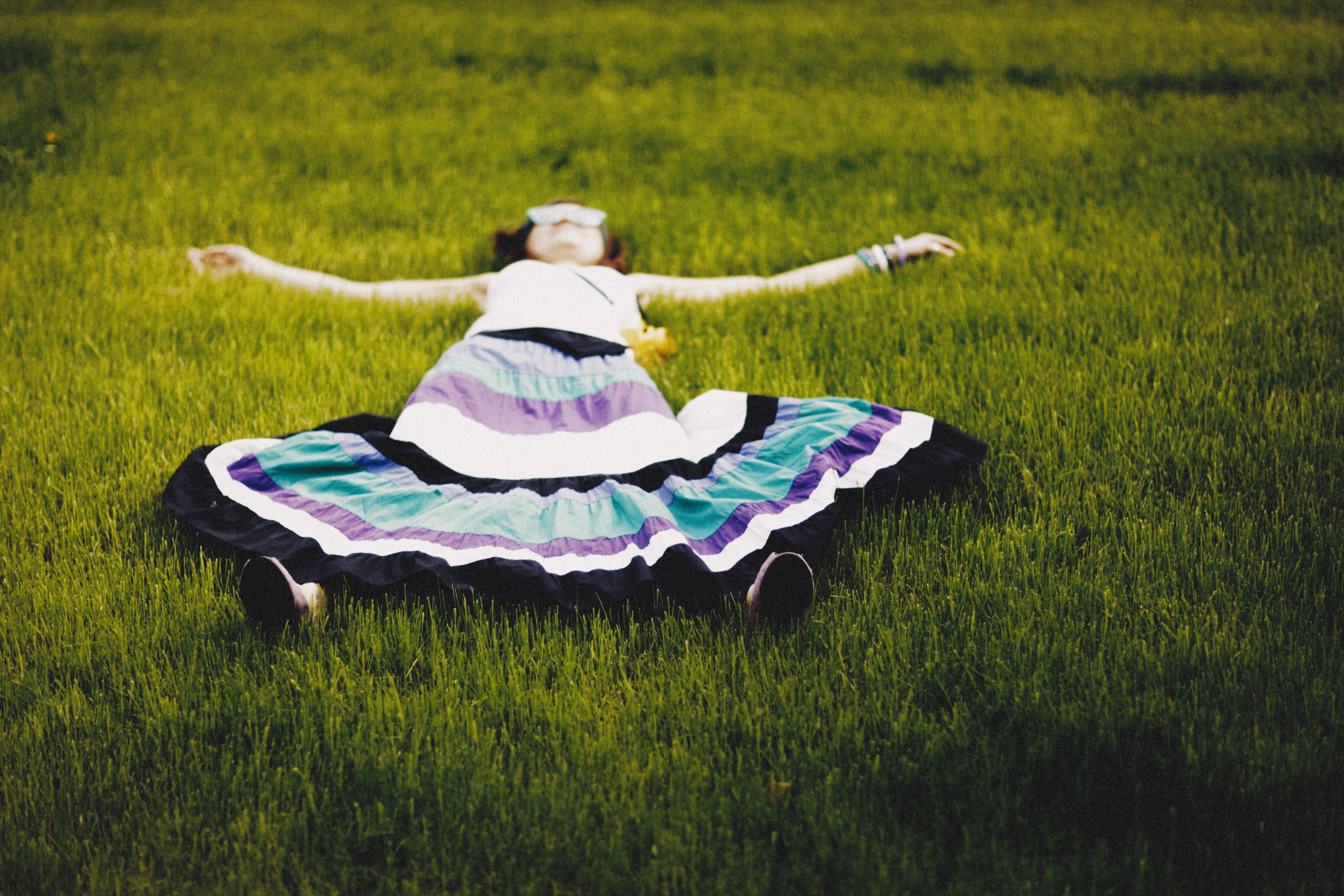A Woman in a Multi Colored Skirt Lying on Green Grass · Free Stock Photo
