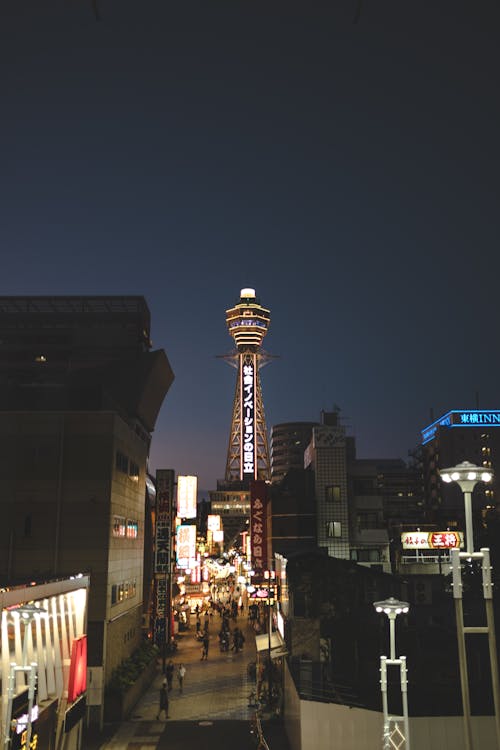 Illuminated Tower Among Buildings at Night