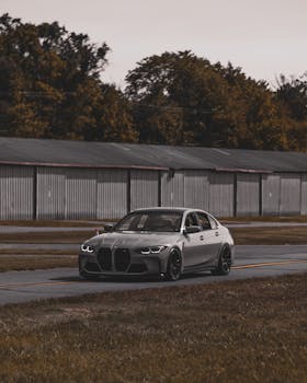 Luxury car driving on an empty road with autumn foliage backdrop, modern elegance.