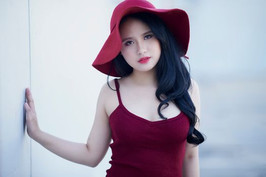 Stylish woman in a red hat and dress posing outdoors, exuding elegance and charm.